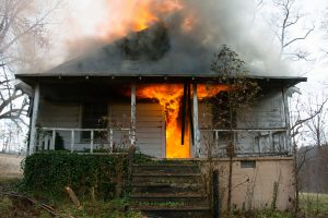 flames rolling out onto the porch of house on fire